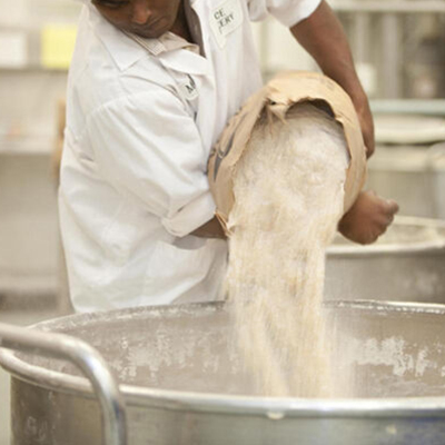 Factory worker pouring flour at ACE Bakery Foodservice production facility that produces artisan sandwich carriers, burger buns, and table breads.